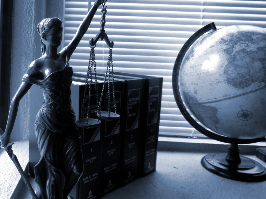 Black and white photo of Lady Justice and a globe on a desk.