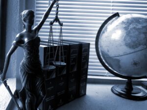 Black and white photo of Lady Justice and a globe on a desk.