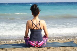 A woman meditating at the beach.